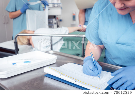 Nurse writing pre surgery report on file 78612559