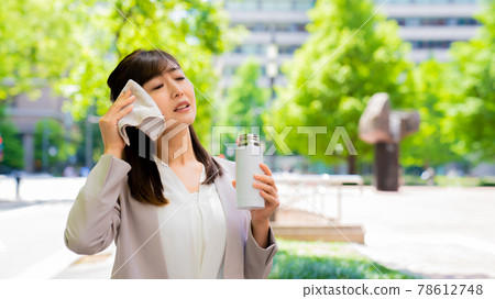 在外面擦汗的同時補充水分的女商人 78612748