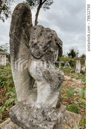 Close up view of broken weathered tombstone with stone angel on old abandoned city or village cemetery. Weathered gravestone on abandoned graveyard. Selective focus, sacral art details 78612798