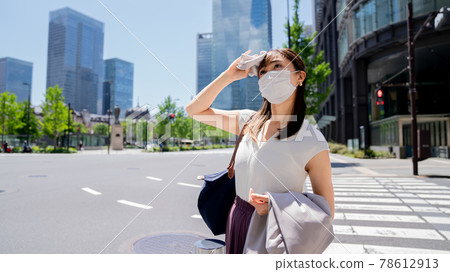 一個戴著面具的女人，熱得擦汗 78612913