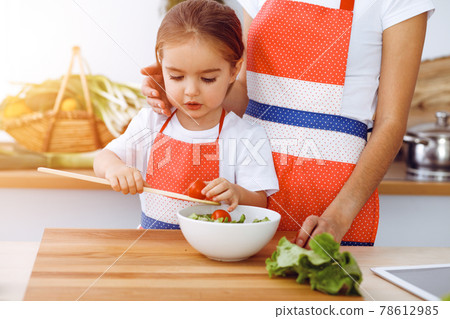 Happy woman and her daughter making healthy vegan salad and snacks for family feasting in sunny kitchen. Christmas, New year, Thanksgiving, Anniversary, Mothers Day. Healthy meal cooking concept Happy woman and her daughter making healthy vegan salad and snacks for family feasting in sunny kitchen. Christmas, New year, Thanksgiving, Anniversary, Mothers Day. Healthy meal cooking concept 78612985