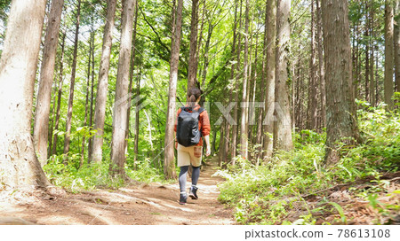 Back view of a young woman hiking in the mountains 78613108