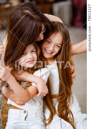 mom hugs daughters rides on a swing in the loft. mother's day mom hugs daughters rides on a swing in the loft. mother's day 78613327
