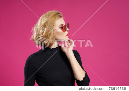 Pretty woman in dark glasses bright makeup black jacket close-up pink background 78614586
