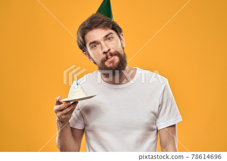 Handsome man with a beard and in a cap celebrating a birthday party yellow background Handsome man with a beard and in a cap celebrating a birthday party yellow background 78614696
