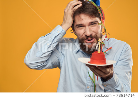 Birthday boy in a cap with a birthday cake in his hand and a candle Birthday boy in a cap with a birthday cake in his hand and a candle 78614714