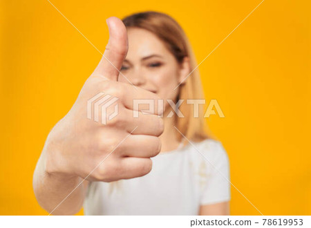 Happy woman showing thumb up positive gesture on yellow background 78619953