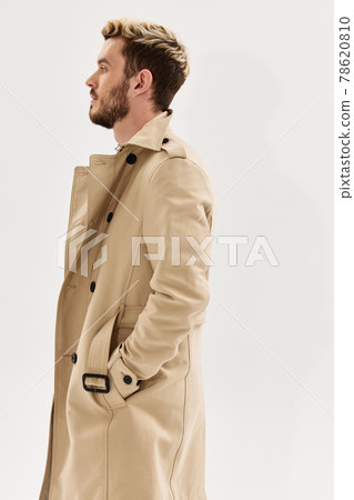 man holding hands in pockets of beige coat side view light background man holding hands in pockets of beige coat side view light background 78620810