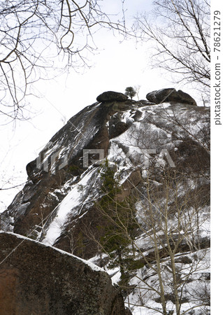 Massive rock partially covered with snow in the park. Massive rock partially covered with snow in the park. 78621279