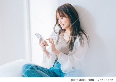 A young woman using a smartphone 78622776