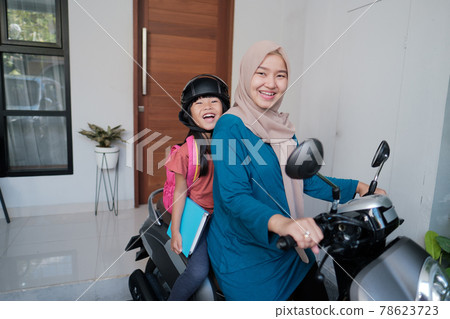 muslim mother taking her daughter to school by motorcycle in the morning muslim mother taking her daughter to school by motorcycle in the morning 78623723