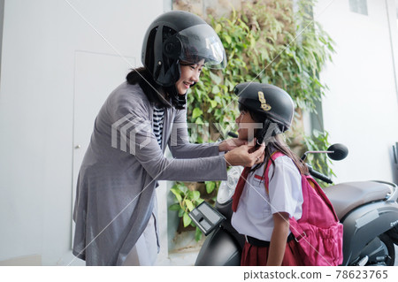 mother taking her daughter to school by motorcycle in the morning 78623765