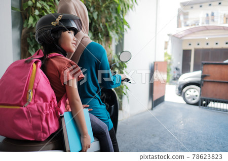 muslim mother taking her daughter to school by motorcycle in the morning muslim mother taking her daughter to school by motorcycle in the morning 78623823