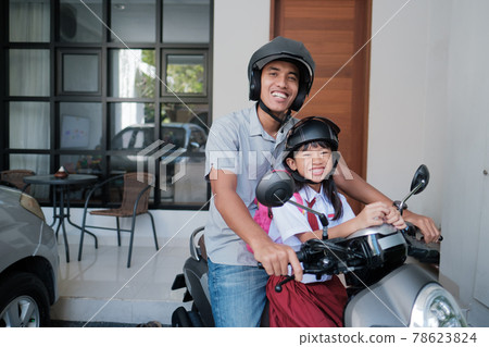 father taking his daughter to school by motorcycle in the morning father taking his daughter to school by motorcycle in the morning 78623824