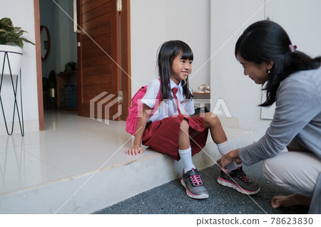 mother help her daughter to wear a shoes in the morning mother help her daughter to wear a shoes in the morning 78623830