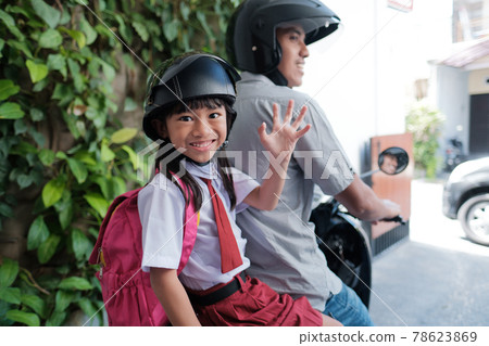 father taking his daughter to school by motorcycle in the morning father taking his daughter to school by motorcycle in the morning 78623869