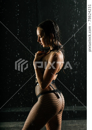 Female in the white shirt with water drop in a dark room illuminated by light Female in the white shirt with water drop in a dark room illuminated by light 78624231