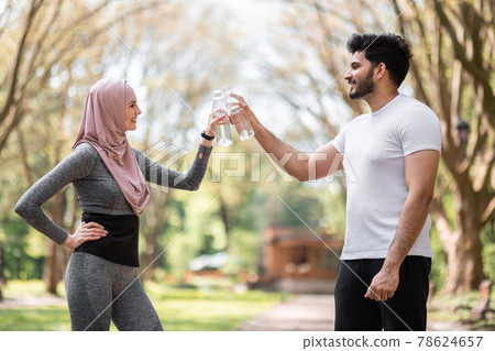 Muslim man and woman making cheers with water bottles 78624657