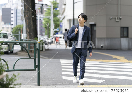 Young man walking in the city with a backpack Young man walking in the city with a backpack 78625083