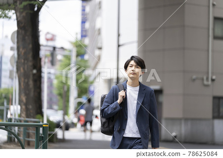Young man walking in the city with a backpack 78625084