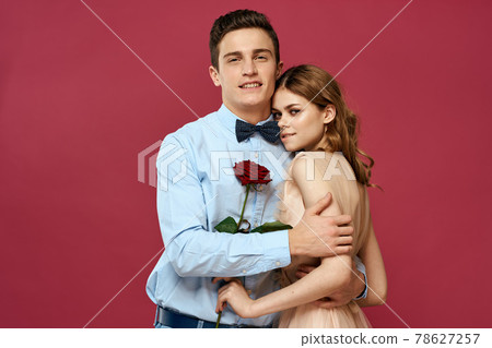 enamored man and woman with a red flower on a pink background hug each other Copy Space 78627257