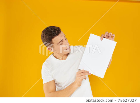 Guy with a white sheet of paper on a yellow background blank business card advertising 78627327