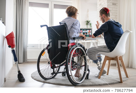 Rear view of disabled people sitting at the table indoors at home, video call concept. 78627794