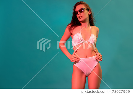 Woman in white swimsuit and sunglasses on blue background with copyspace 78627969