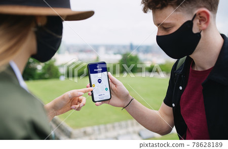 Young couple travelers with smartphone looking for accomodation in city on holiday, coronavirus concept. Young couple travelers with smartphone looking for accomodation in city on holiday, coronavirus concept. 78628189