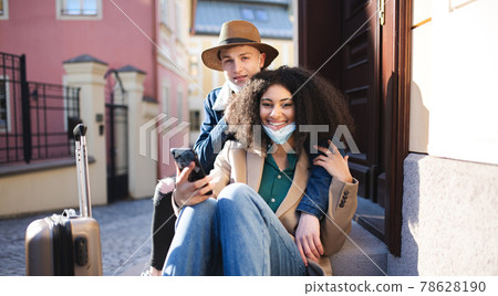 Young couple tourists with smartphone on holiday in old town, coronavirus concept. Young couple tourists with smartphone on holiday in old town, coronavirus concept. 78628190