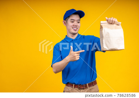 Asian delivery man holding fast food bag over yellow isolate background. Work from home and delivery concept. Asian delivery man holding fast food bag over yellow isolate background. Work from home and delivery concept. 78628586