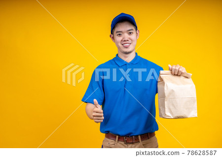 Asian delivery man holding fast food bag over yellow isolate background. Work from home and delivery concept. 78628587