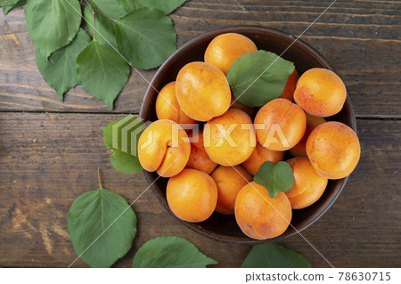 Delicious ripe apricots in a clay bowl on the table close-up. Delicious ripe apricots in a clay bowl on the table close-up. 78630715