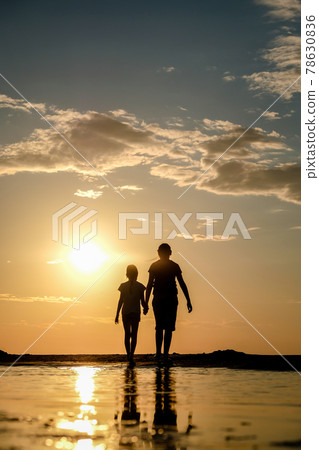 Silhouette of two sisters holding hands who standing on the beach at the sunset. Vertical photo Silhouette of two sisters holding hands who standing on the beach at the sunset. Vertical photo 78630836