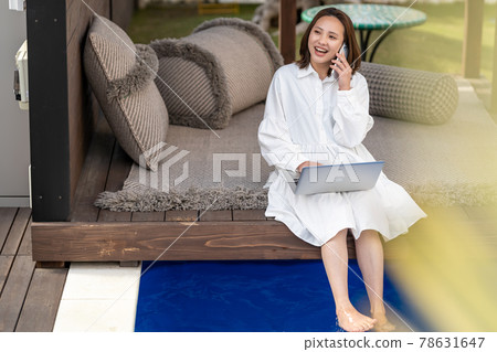 Worcation poolside business woman smartphone call 78631647
