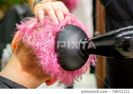 Hairdresser drying pink hair of client Hairdresser drying pink hair of client 78632122