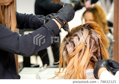 Hairdresser coloring hair of woman 78632125