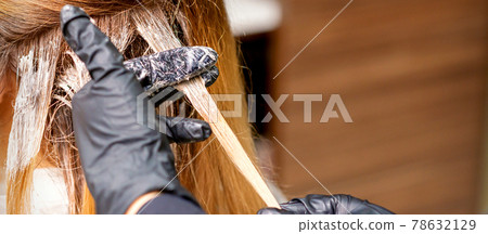 Hairdresser applying dye to strand of hair Hairdresser applying dye to strand of hair 78632129