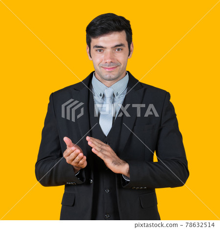 Young businessman in gray shirt and black suit clapping hand and starts a successful business project. The concept of business relations Portrait on a yellow background with studio lights Young businessman in gray shirt and black suit clapping hand and starts a successful business project. The concept of business relations Portrait on a yellow background with studio lights 78632514