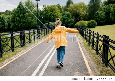 Happy teenage girl learning to ride a skateboard in the city park. Happy teenage girl learning to ride a skateboard in the city park. 78633947