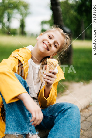 Portrait of a cute blonde teenage girl with ice cream on a walk in the park. Child outdoors 78633950