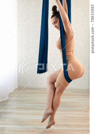 Graceful girl trainer, sits in an air hammock, air yoga 78633993