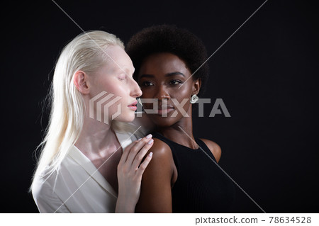 Caucasian and african american young woman isolated on black background. Caucasian and african american young woman isolated on black background. 78634528