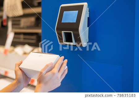 A faceless woman uses a price scanner on the wall 78635183