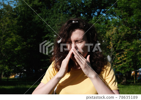 Girl sneezes because of the poplar fluff. Allergic reaction to poplar fluff 78635189