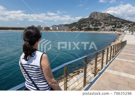 Pretty Spanish tourist woman looking at seascape from small town L Estartit 78635296
