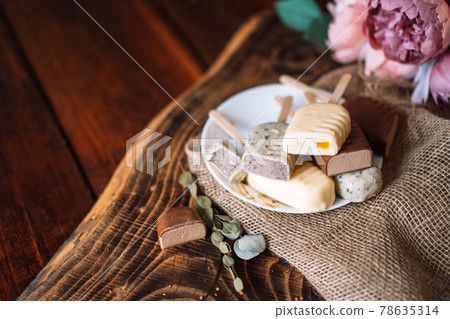 Still life of chocolate popsicle lying on a plate on a wooden table Still life of chocolate popsicle lying on a plate on a wooden table 78635314