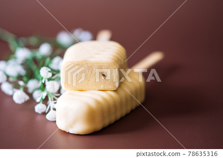 White Chocolate Popsicles cut with filling lying on top of each other on brown background White Chocolate Popsicles cut with filling lying on top of each other on brown background 78635316