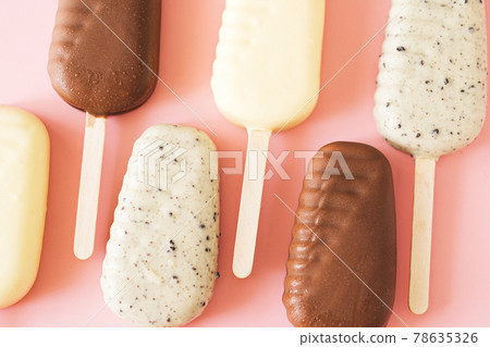 Line of milk and white chocolate popsicles on light pink background, top view Line of milk and white chocolate popsicles on light pink background, top view 78635326