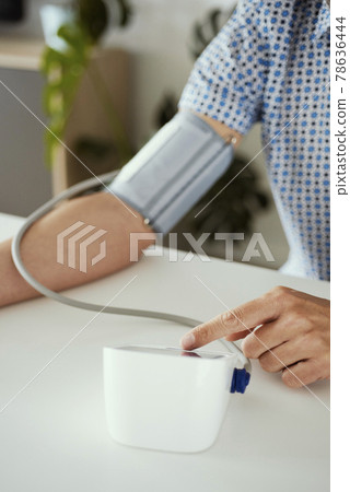 man measures his blood pressure at home 78636444